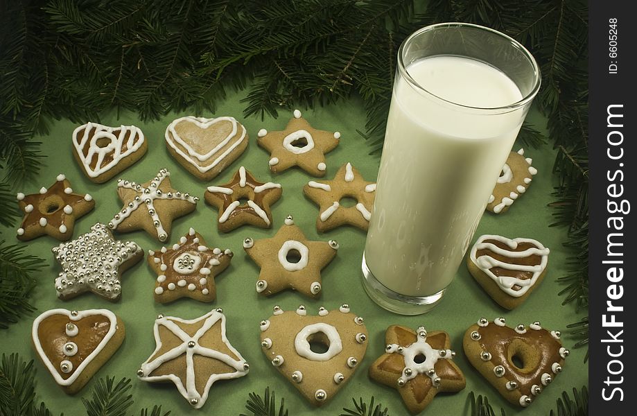 A variety of decorated Christmas cookies with a glass of milk surrounded by fir branches. A variety of decorated Christmas cookies with a glass of milk surrounded by fir branches