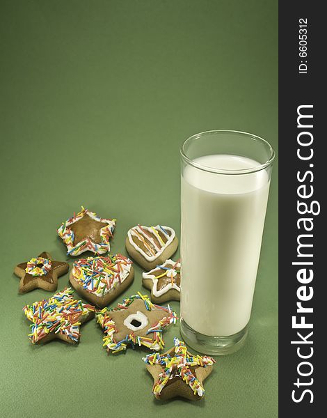 Christmas cookies and a glass of milk isolated against green paper. Christmas cookies and a glass of milk isolated against green paper