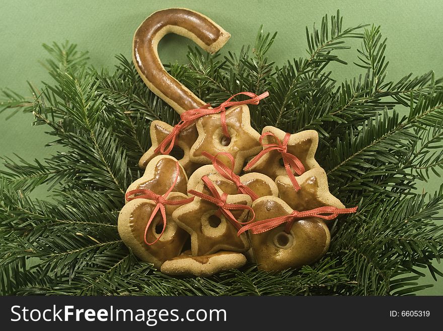 A pile of gingerbread cookies nestled in nest of fir branches and isolated on green paper. A pile of gingerbread cookies nestled in nest of fir branches and isolated on green paper