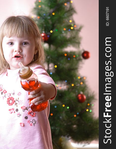 Baby with bottle near christmas tree