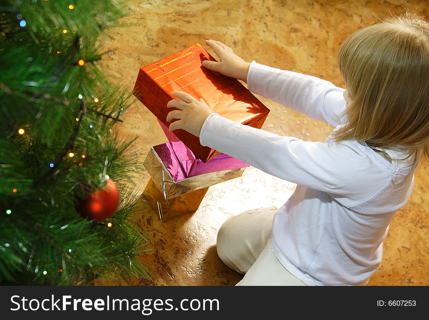 Girl and gift box near christmas tree