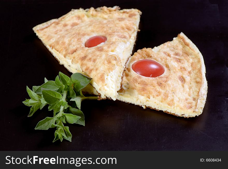 Slices of Frittata omelet made with eggs, potato and onion and garnished with cherry tomatoes and herbs. Slices of Frittata omelet made with eggs, potato and onion and garnished with cherry tomatoes and herbs