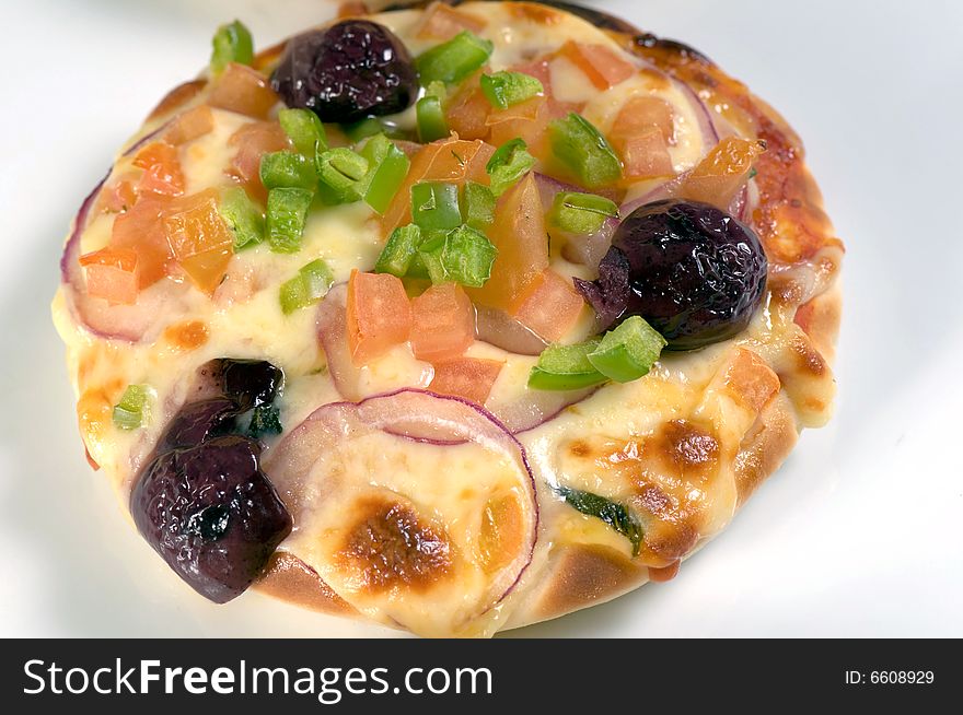 A small Mediterranean pizza with dark olives, green pepper, tomato and onion. A small Mediterranean pizza with dark olives, green pepper, tomato and onion