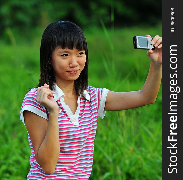 A girl taking a photo of herself with a handphone camera. A girl taking a photo of herself with a handphone camera.