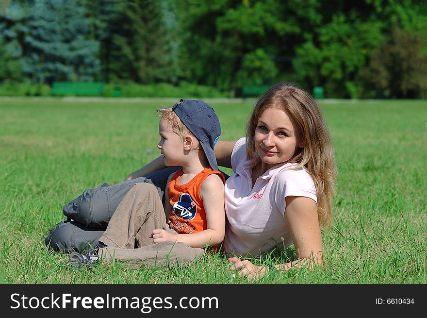 Mother and son are lying on the green grass