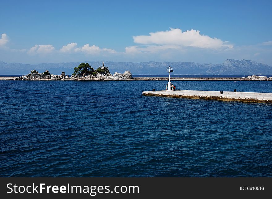 Promenade and the port with a beacon on the shore of the Adriatic. Promenade and the port with a beacon on the shore of the Adriatic