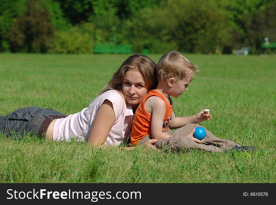 Mother and son are lying on the grass