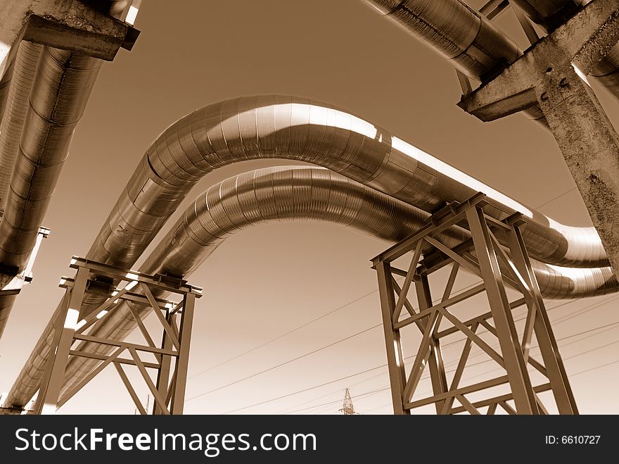 Industrial pipelines on pipe-bridge against blue sky.