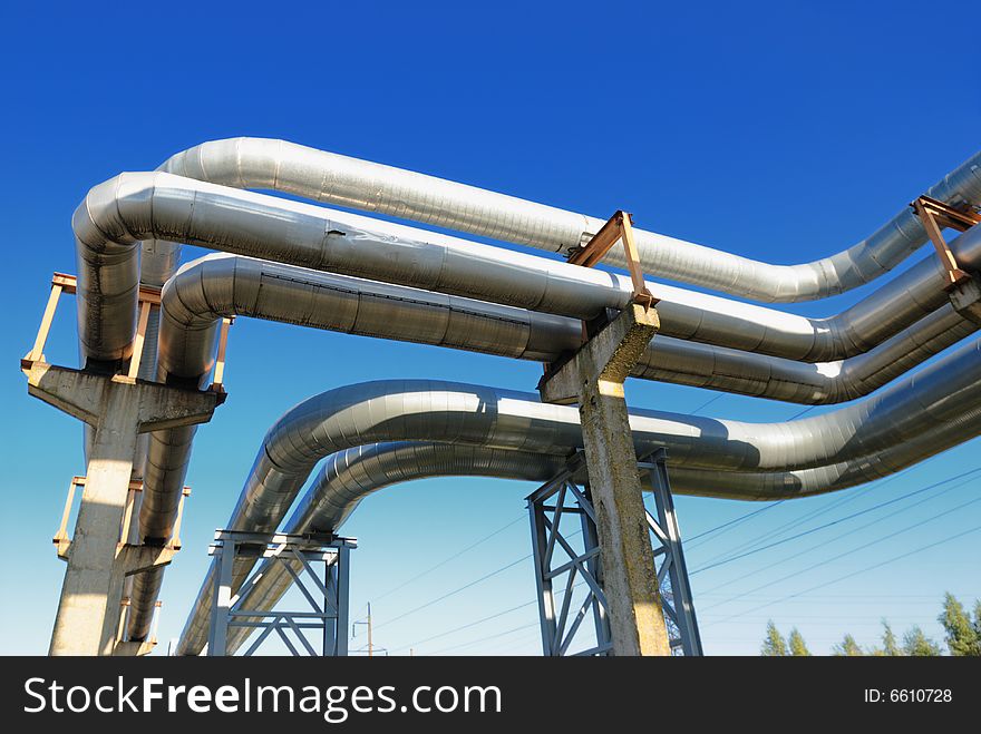 Industrial pipelines on pipe-bridge against blue sky.