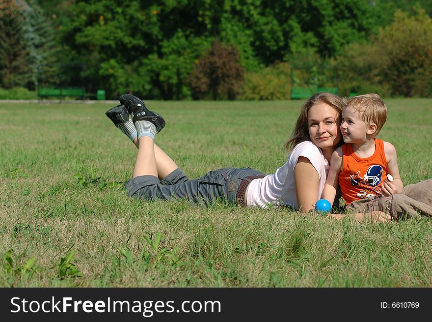 Mother and son are lying on the grass