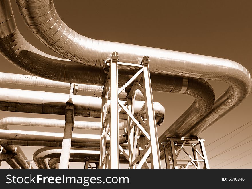 Industrial pipelines on pipe-bridge against blue sky.