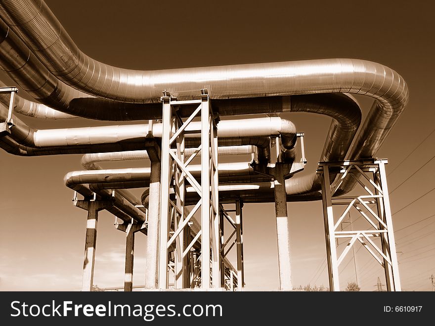 Industrial pipelines on pipe-bridge against blue sky.