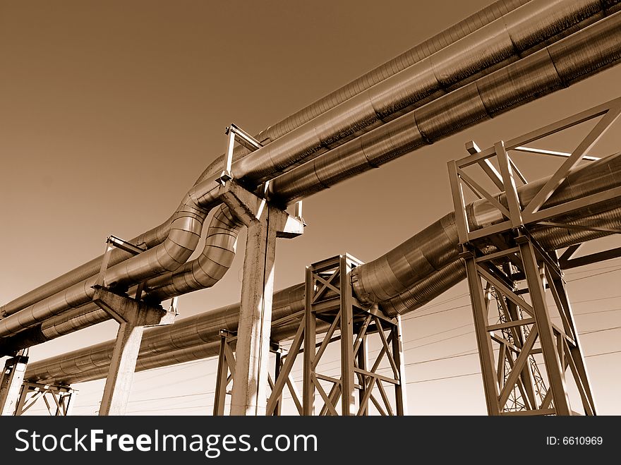 Industrial pipelines on pipe-bridge against blue sky.