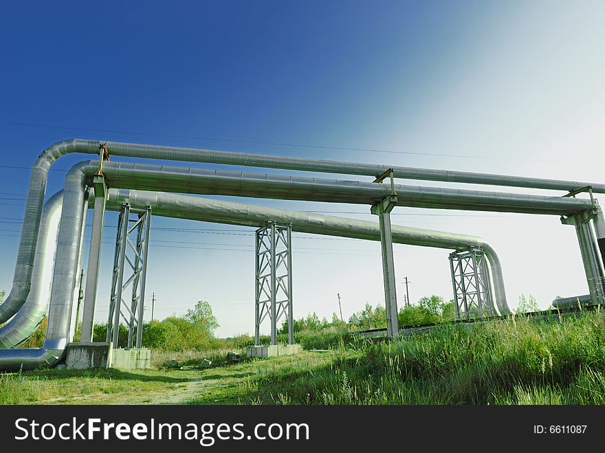 Industrial pipelines on pipe-bridge against blue sky.