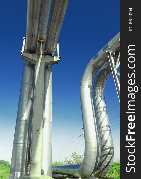 Industrial pipelines on pipe-bridge against blue sky.