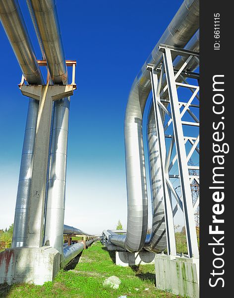 Industrial pipelines on pipe-bridge against blue sky.