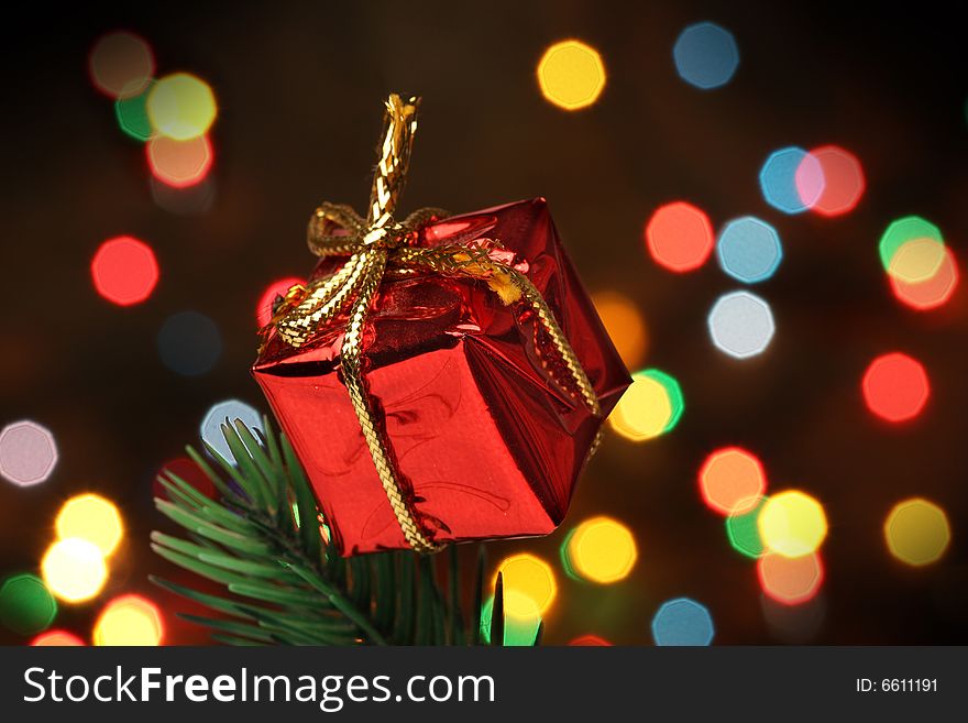 Gift box over a christmas branch tree, lights background