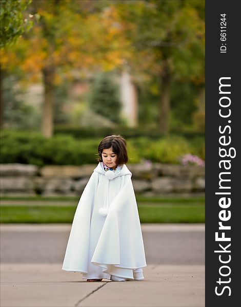 Little girl in white cape outdoors. Little girl in white cape outdoors