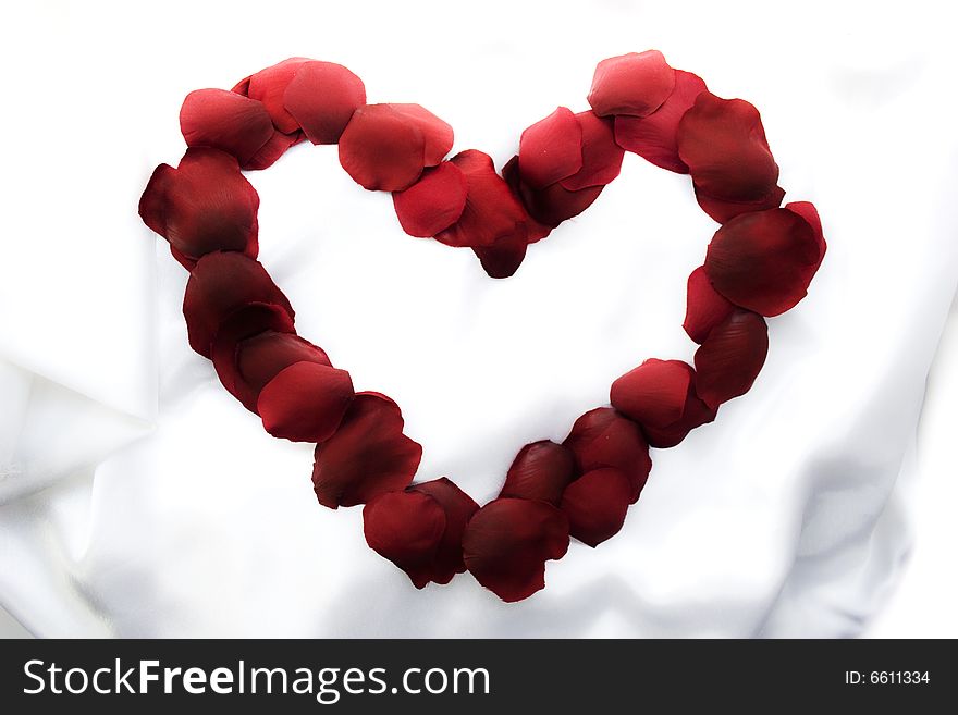 Symbol of heart from rose-petals on white silk