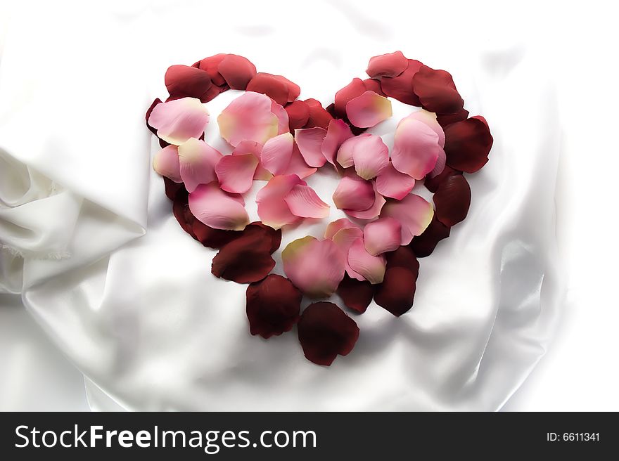Symbol of heart from rose-petals on white silk