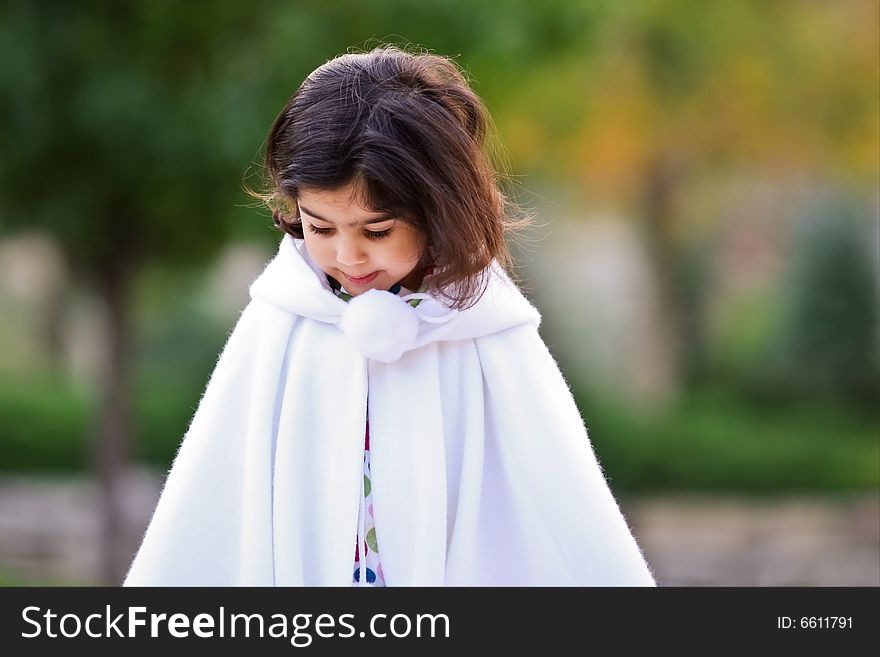 Little girl in white cape outdoors. Little girl in white cape outdoors