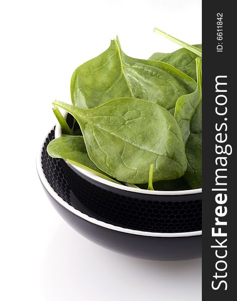 Bowl with fresh raw spinach on a white background. Bowl with fresh raw spinach on a white background.