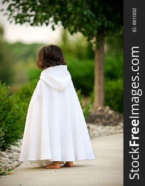 Little girl in white cape outdoors. Little girl in white cape outdoors