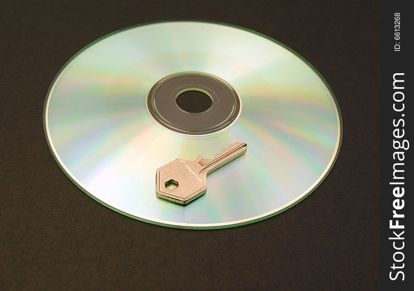 Photograph of a CD with small metal key. Dark background. Photograph of a CD with small metal key. Dark background.