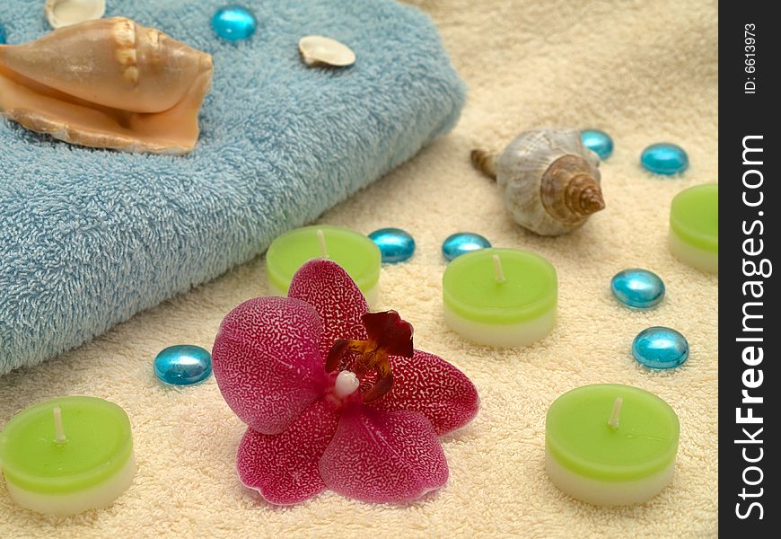 Spa or health farm setting. Towel, candles and orchid.