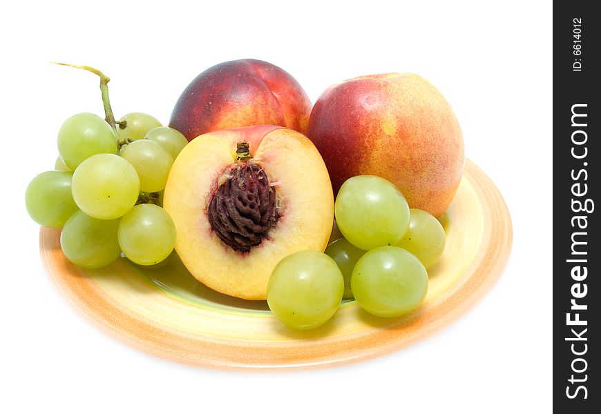 Ripe peaches  and fresh grapes on a plate over white.