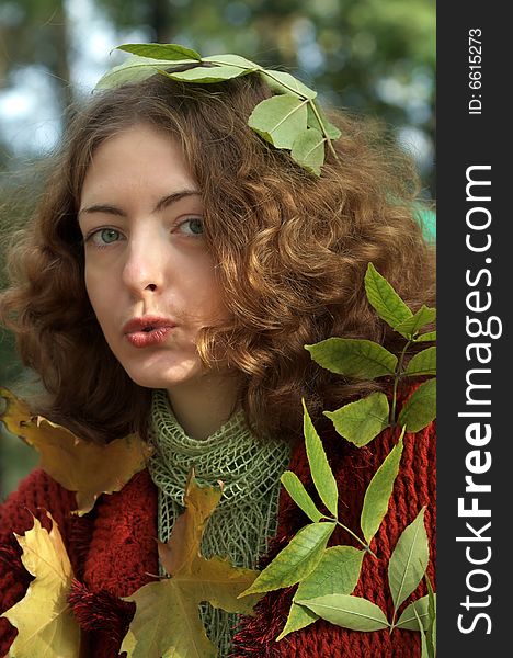 Funny young curly girl shows strange emotions. Her mouth is slightly open, on the shoulders are yellow autumn leaves, the girl is dressed in a vintage red coat. Whisper somethng. Funny young curly girl shows strange emotions. Her mouth is slightly open, on the shoulders are yellow autumn leaves, the girl is dressed in a vintage red coat. Whisper somethng