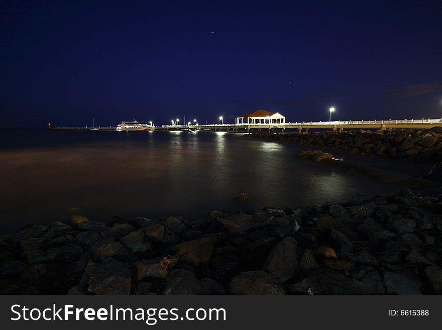 A boardwalk or pier on a seaside location at night. A boardwalk or pier on a seaside location at night