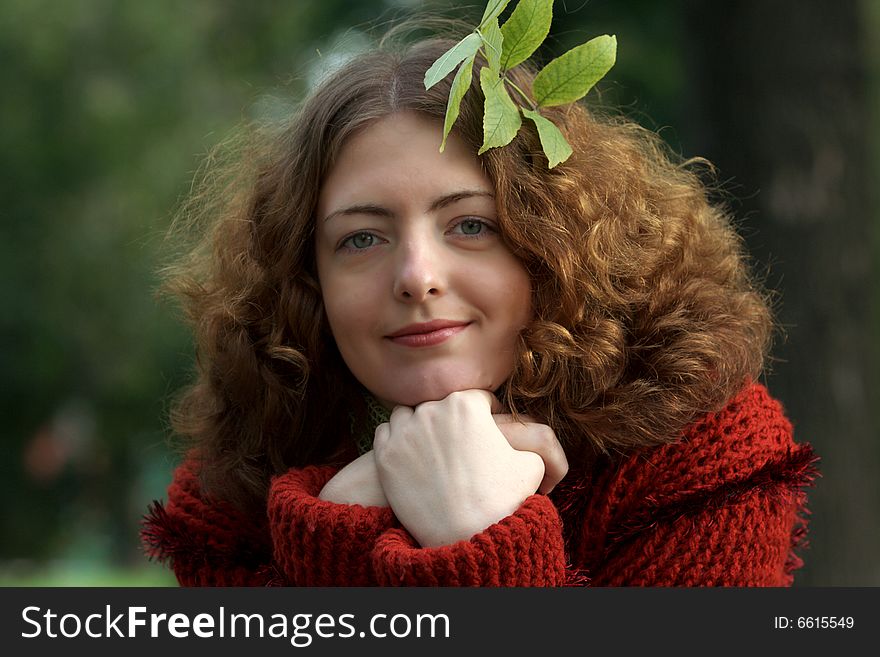 Funny curly young girl in a city park. In a amazing hair the yellow leaf is inserted. autumn cloudy day. Funny curly young girl in a city park. In a amazing hair the yellow leaf is inserted. autumn cloudy day