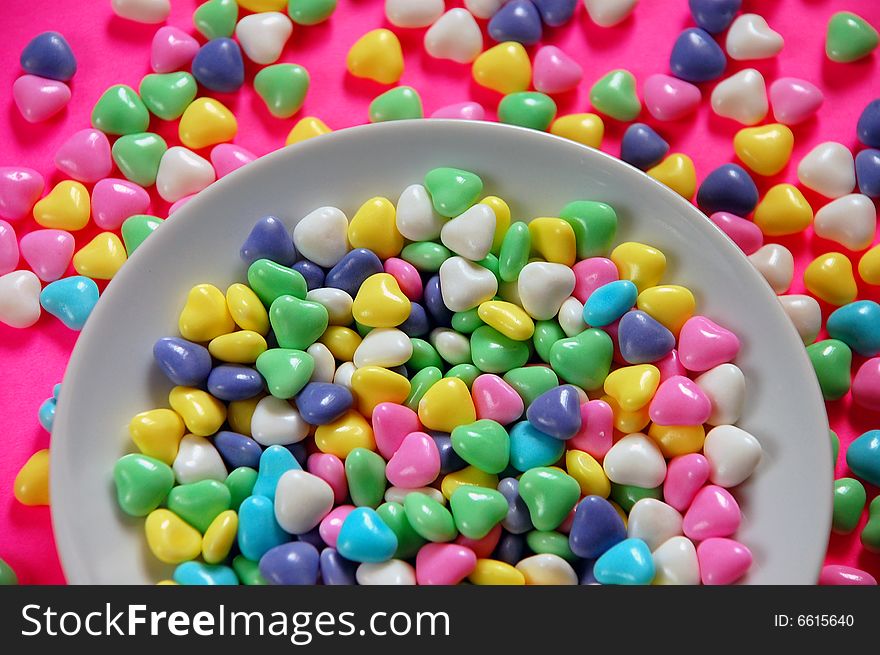 Bowl of candy hearts on pink background