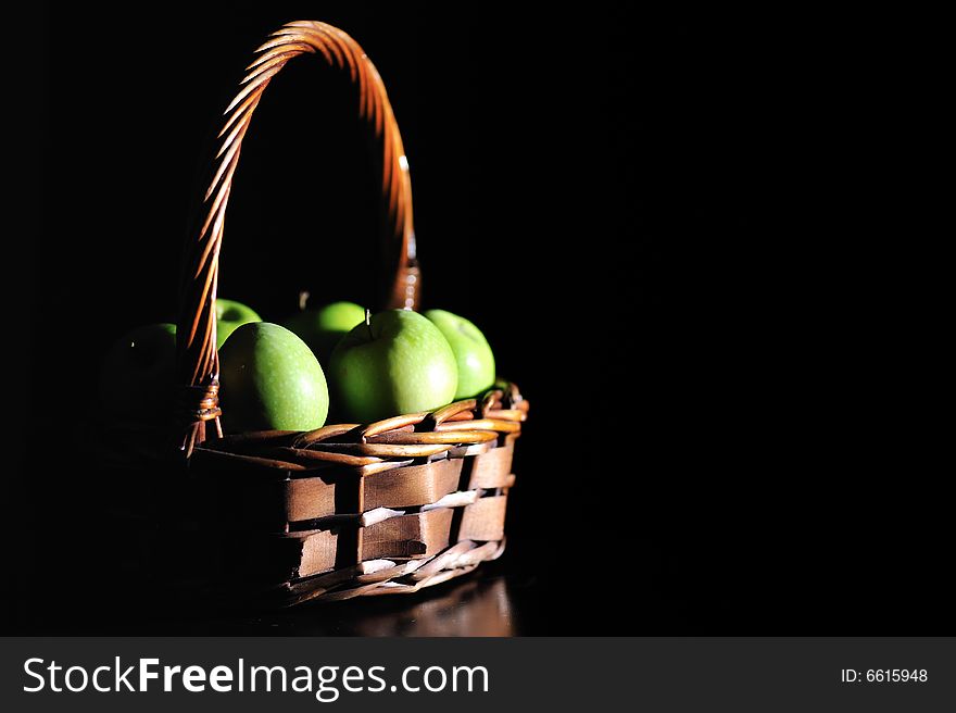 A wooden basket filled with green apples. A wooden basket filled with green apples