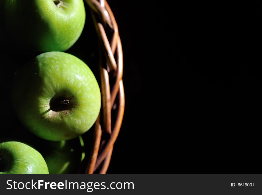 A wooden basket filled with green apples. A wooden basket filled with green apples