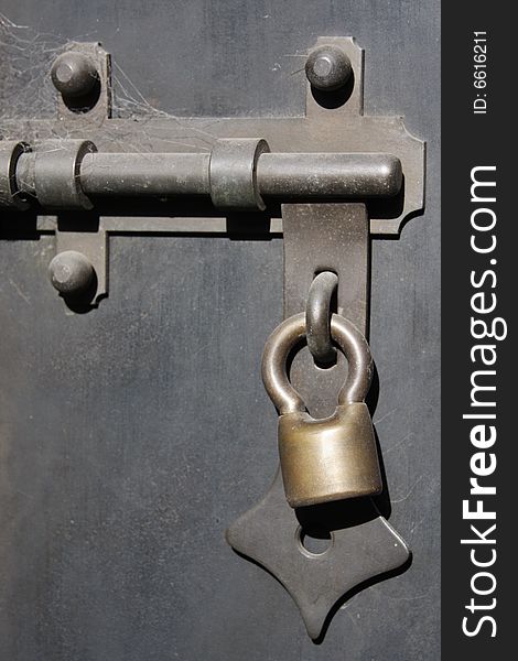 Close up of an old padlock on a black door.