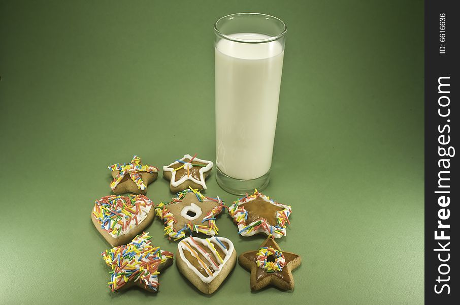 Christmas cookies and a glass of milk isolated against green paper. Christmas cookies and a glass of milk isolated against green paper