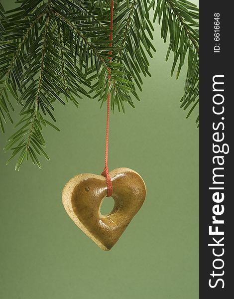 Heart shaped gingerbread cookie hanging by ribbon and isolated against green paper. Heart shaped gingerbread cookie hanging by ribbon and isolated against green paper