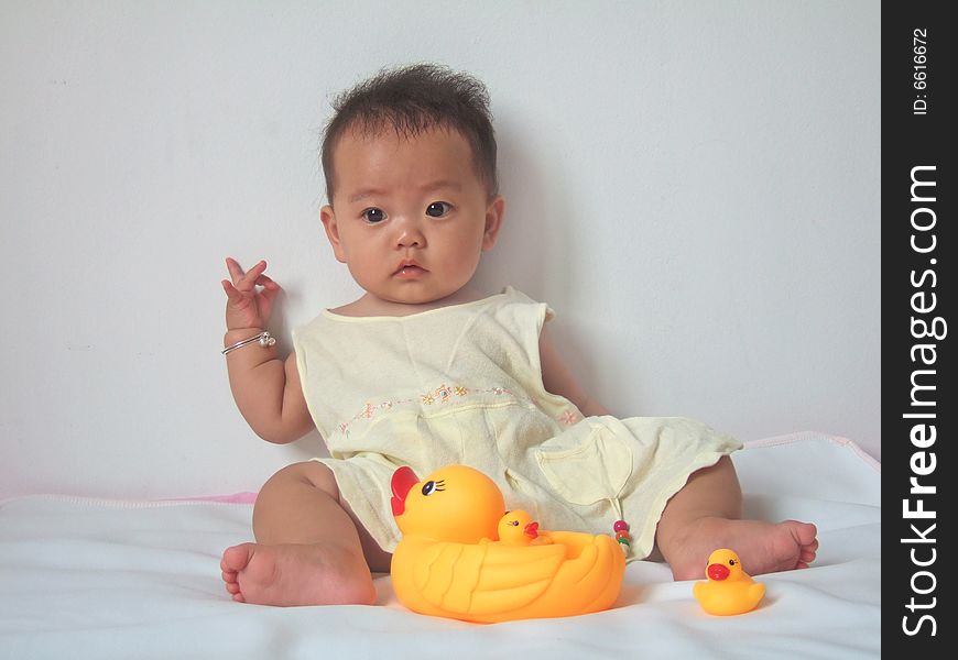 Pretty baby and toy ducks on a bed