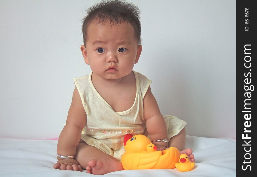 Pretty baby and toy ducks on a bed