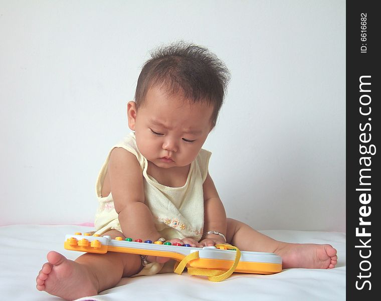 Lovely baby and toy guitar on a bed