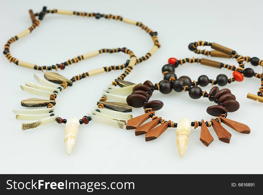 Sundry indian necklace with wooden and crocodilian tooth on white background