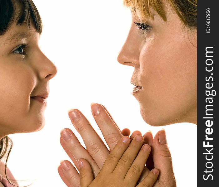 Mother and daughter looking each other in eyes on white