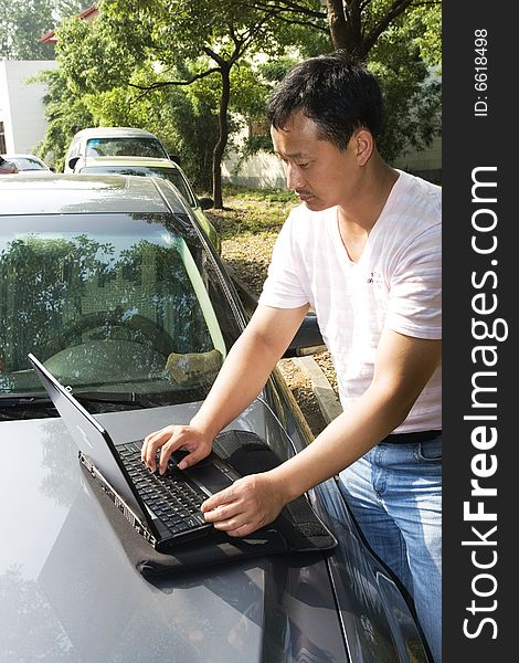 The man working outdoors with a laptop.