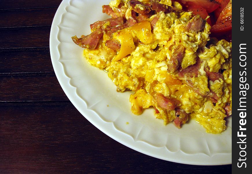 Scrambled eggs meal with tomatoes on plate on brown table. Scrambled eggs meal with tomatoes on plate on brown table.