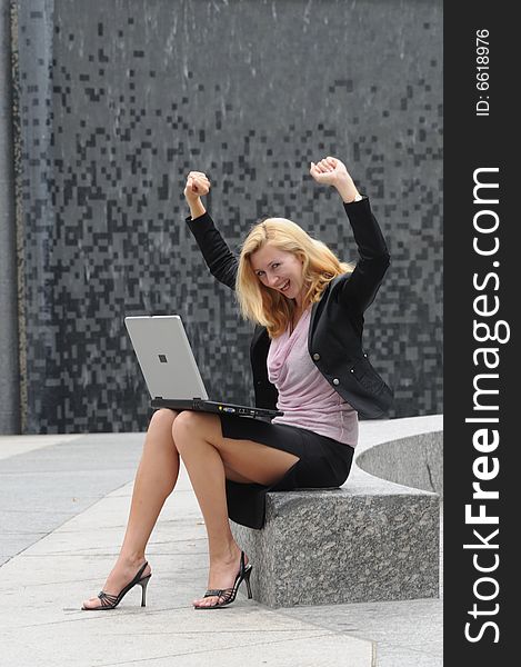 Young business woman gesturing due to successful work on her laptop.