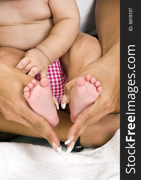 Mother holding her child's feet on an isolated white background