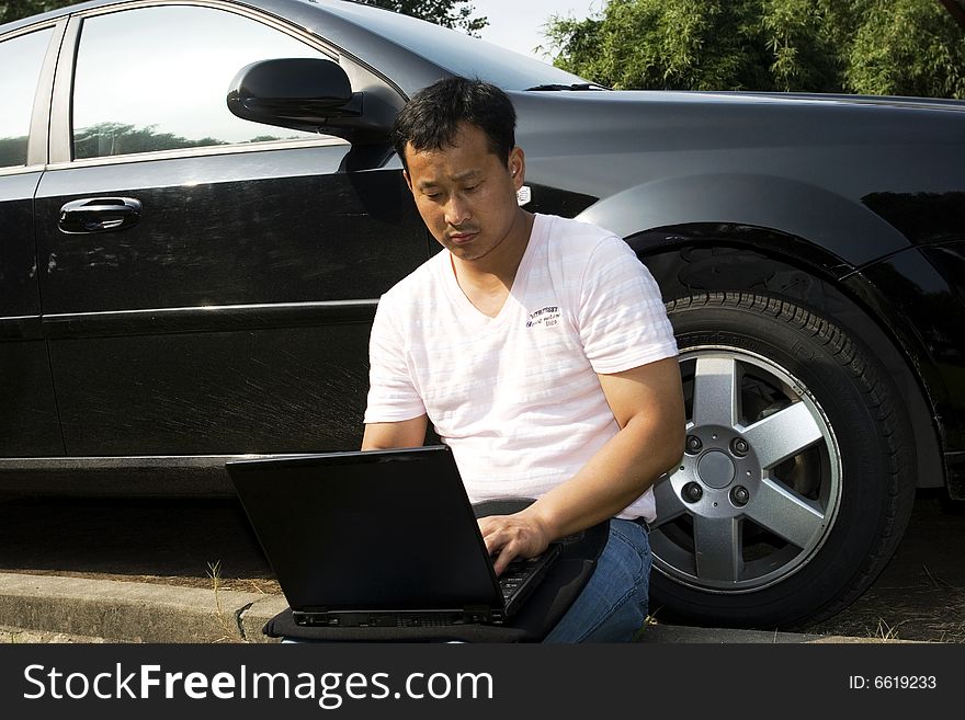 The man working outdoors with a laptop.