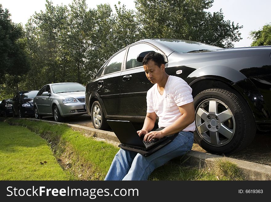 The man working outdoors with a laptop.